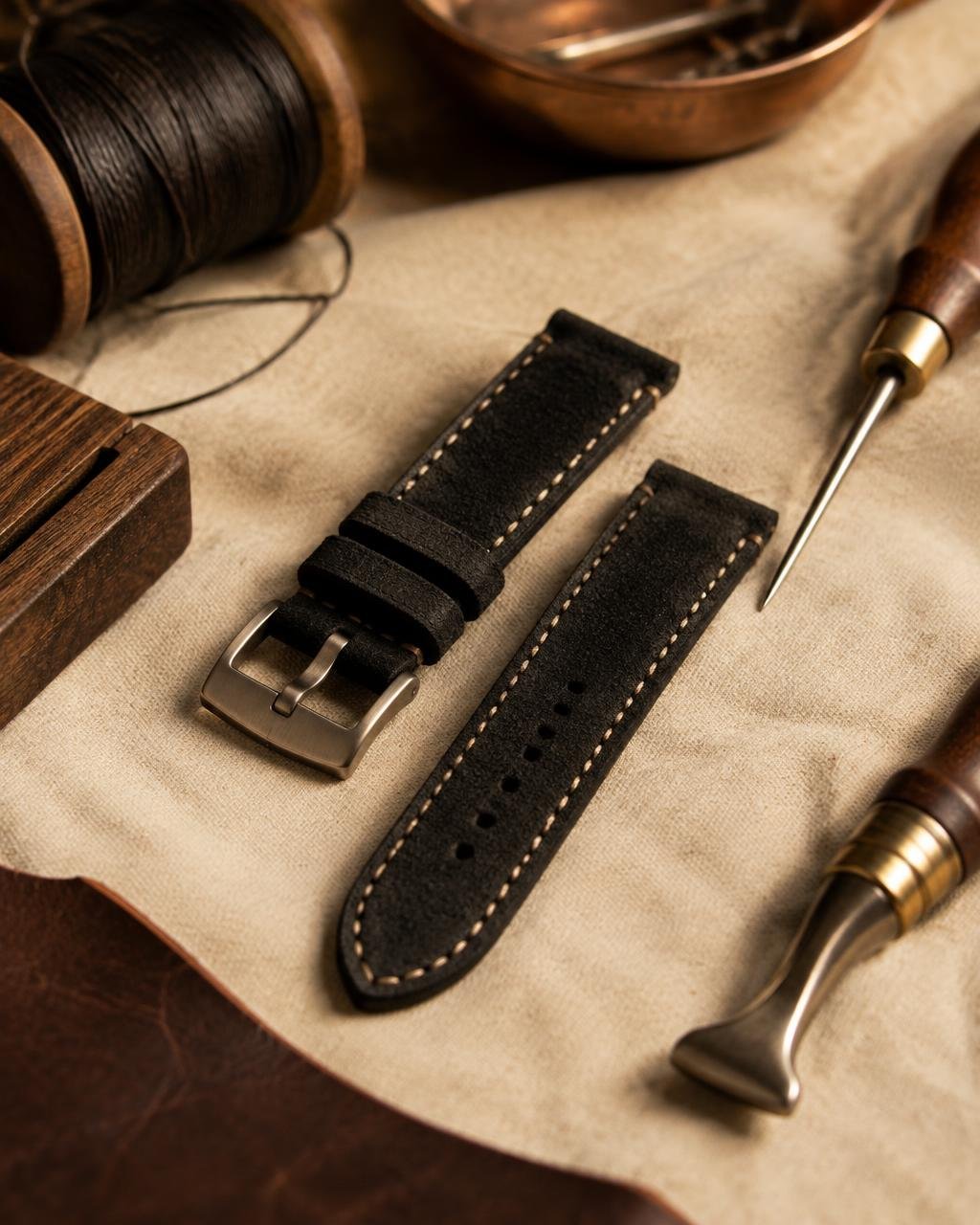Black suede watch strap among leather tools